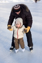 Winter recreation. Father and child skating on rink. Focus is on boy's face